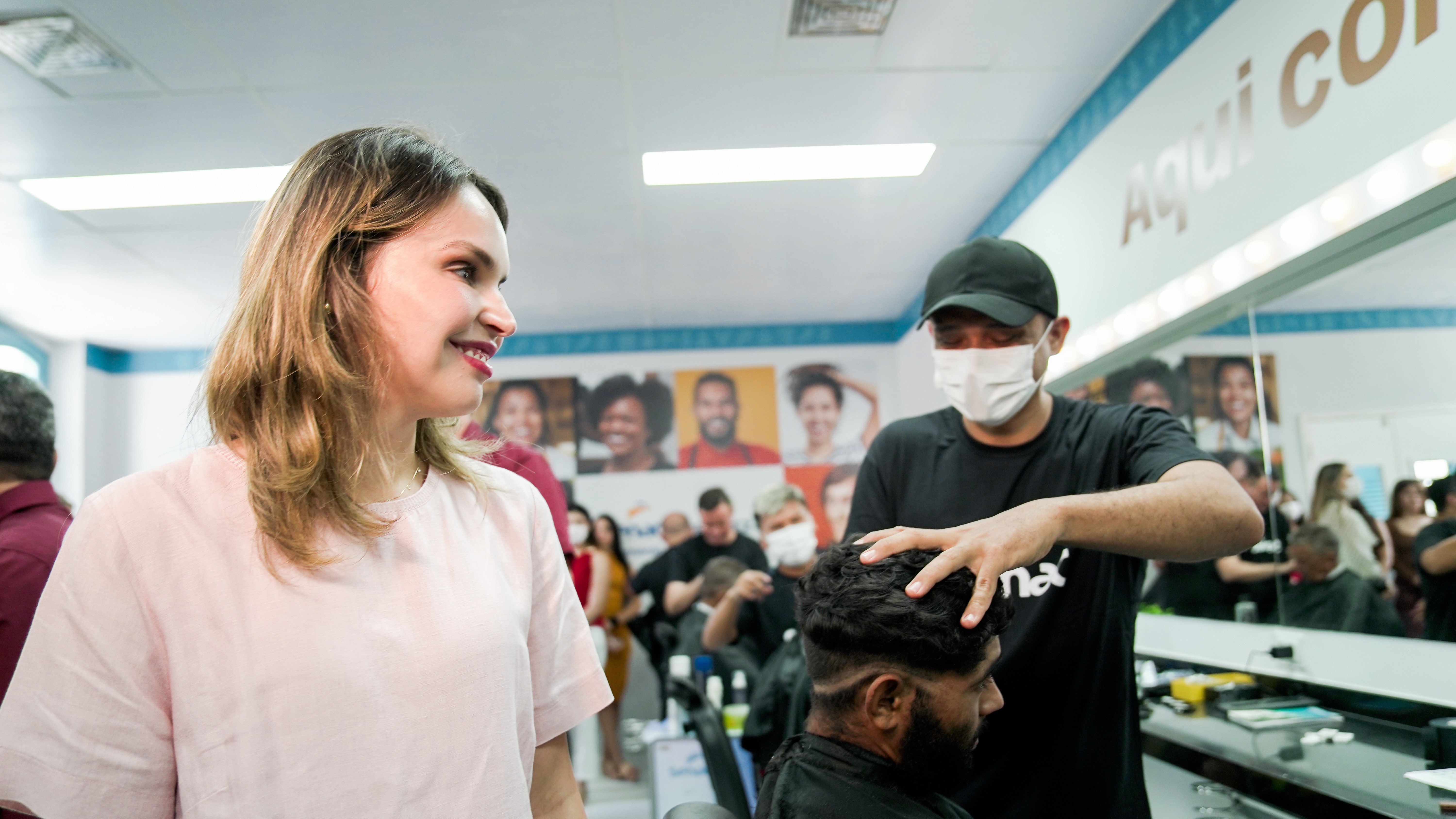 Gabriella Aguiar observa um barbeiro cortar o cabelo de um homem